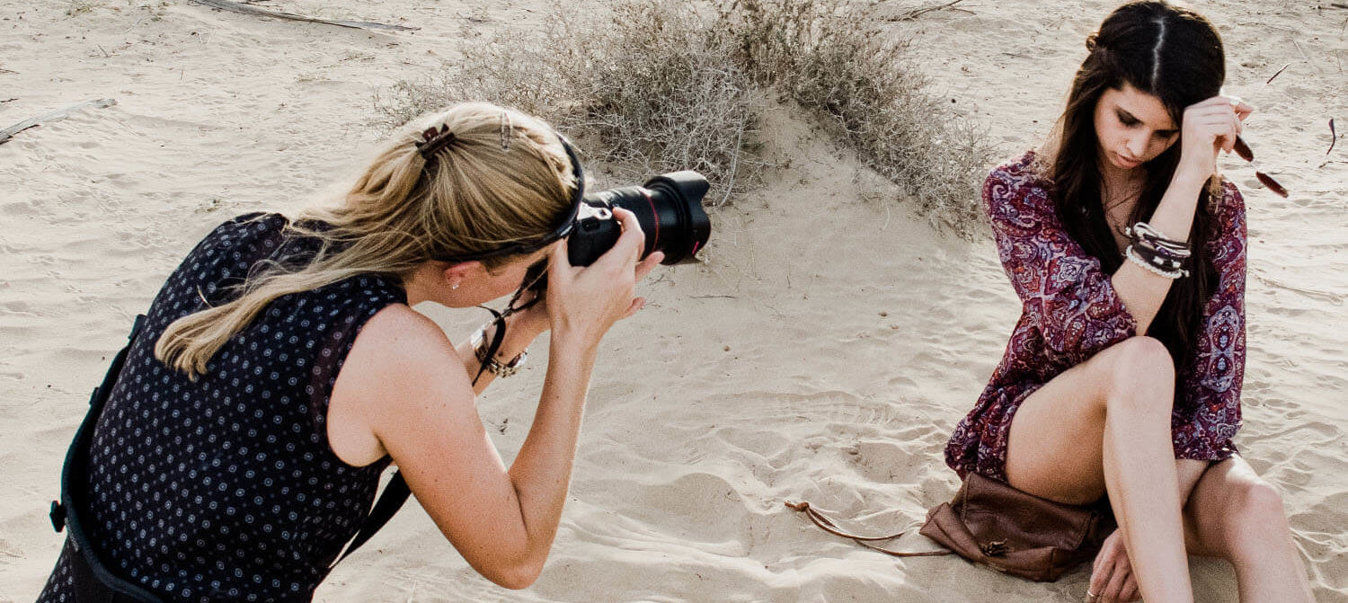 Fotograf Helen Shippey med en modell sittandes i öknen i Dubai